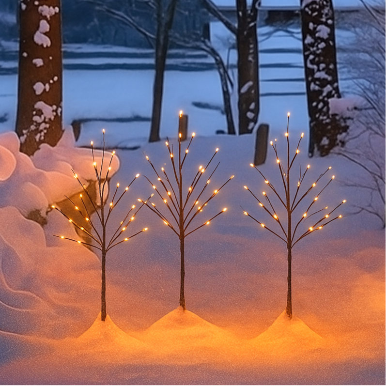 Decorative light trees in a snowy landscape with a house in the background.
